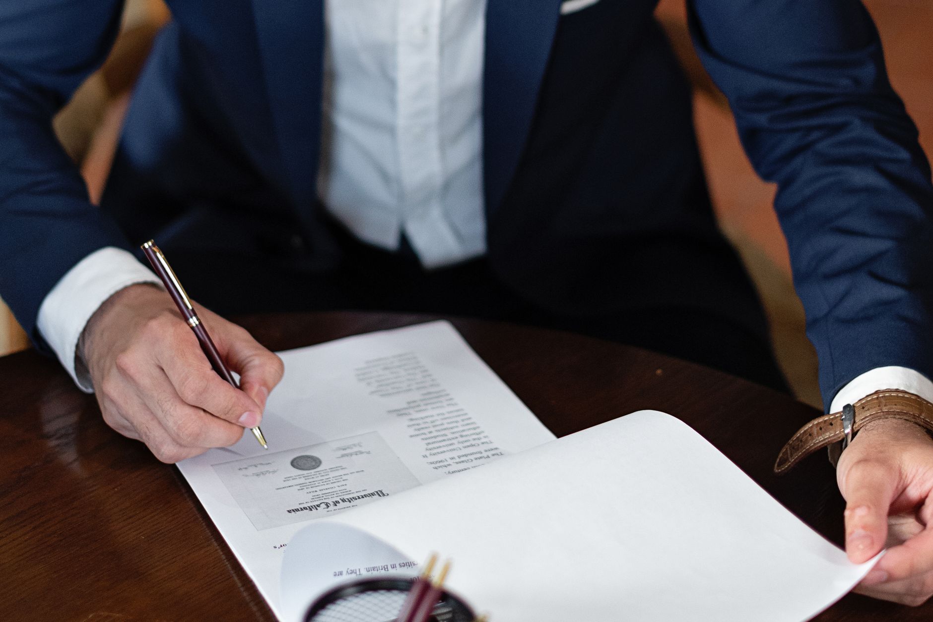 Persona firmando documentos en un escritorio de oficina