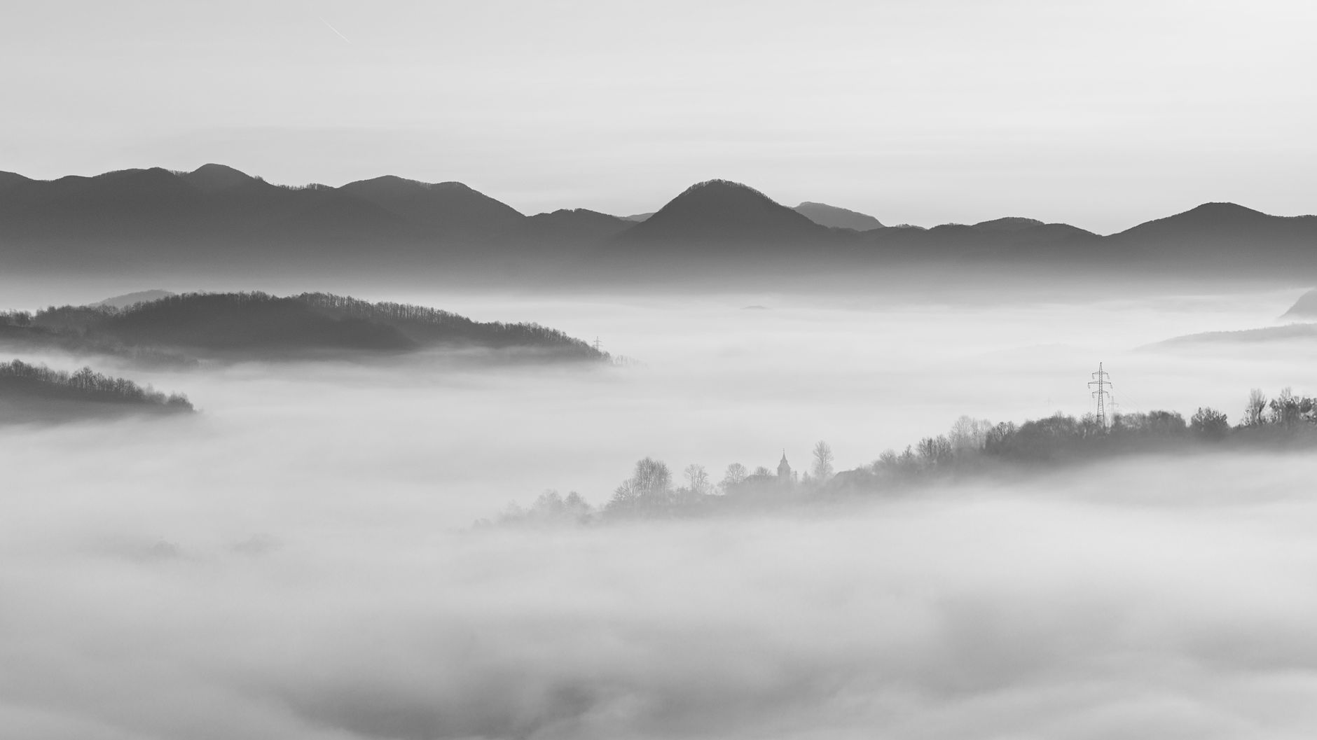 Valle cubierto de niebla con montañas al fondo, en blanco y negro